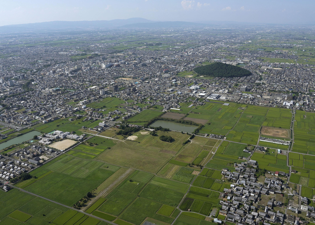 This shows Fujiwara Palace Ruins, foreground, with Mr. Miminashi, background, in Kashihara, Nara prefecture, western Japan, on Sept. 9, 2024. (Kyodo News via AP)