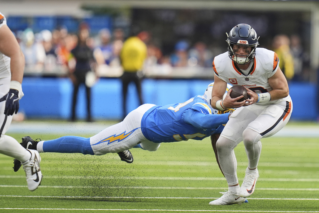 Denver Broncos quarterback Bo Nix (10) evades the tackle from Los Angeles Chargers linebacker Kyle Kennard (54) during the second half of an NFL football game Sunday, Sept. 21, 2025, in Inglewood, Calif. (AP Photo/Gregory Bull)