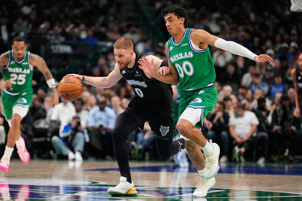 Minnesota Timberwolves guard Donte DiVincenzo (0) drives to the basket as Dallas Mavericks' Max Christie (00) defends in the first half of an NBA basketball game Wednesday, Jan. 28, 2026, in Dallas. (AP Photo/Tony Gutierrez)