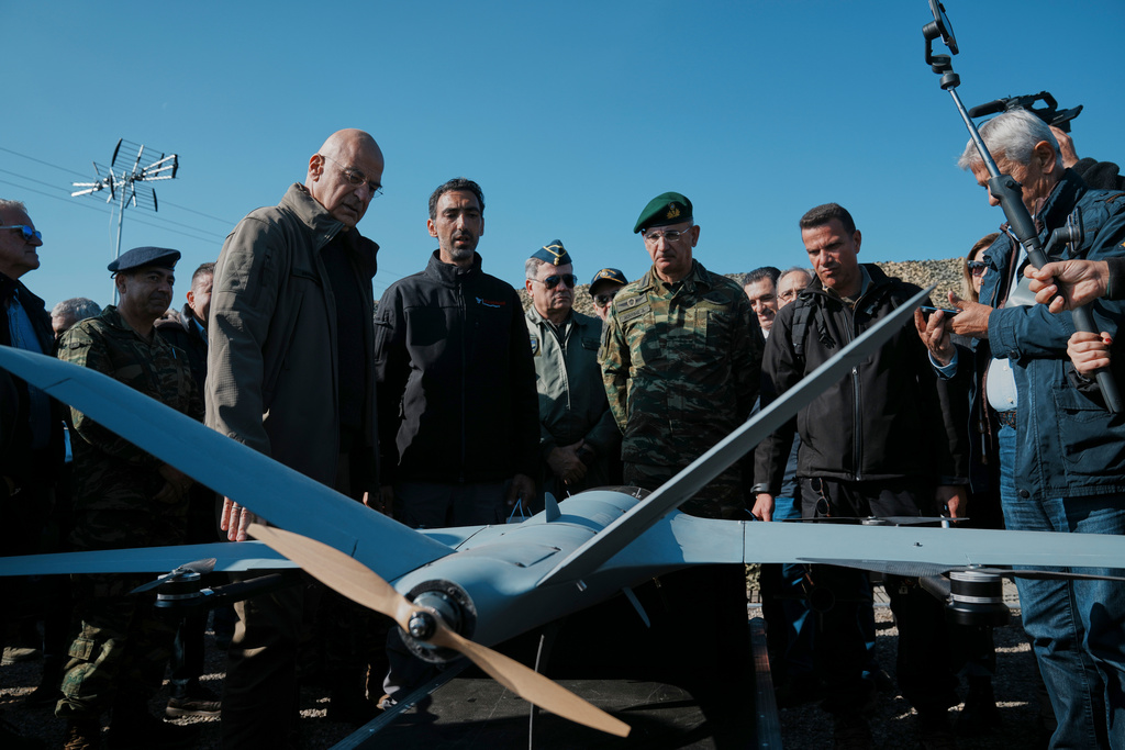 Greece's Defense Minister Nikolaos Dendias, left, stands behind a drone during a live-fire exercise near the northeastern city of Alexandroupolis, Greece testing domestically-developed drones and counter-drone systems as part of NATO's modernization efforts on Friday, Nov. 14, 2025. (AP Photo/Thanassis Stavrakis)