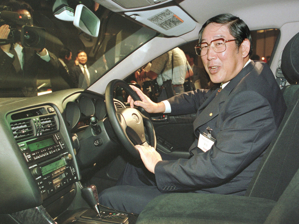 FILE - Hiroshi Okuda, then, president of Toyota Motor Corp., smiles as he sits at the steering wheel of the "Aristo," Toyota's remodeled sports sedan during a press conference at a Tokyo hotel, Aug. 27, 1997. (AP Photo/Shizuo Kambayashi, File)