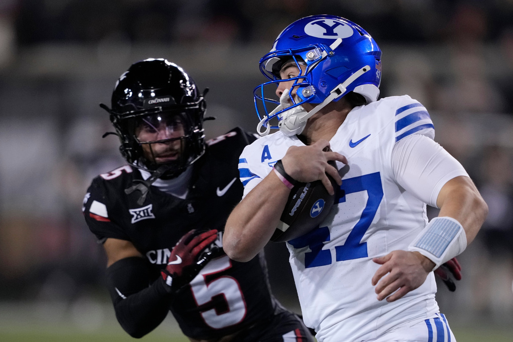 BYU quarterback Bear Bachmeier (47) eyes Cincinnati safety Christian Harrison (5) as he runs with the ball during the first half of an NCAA college football game Saturday, Nov. 22, 2025, in Cincinnati. (AP Photo/Carolyn Kaster)