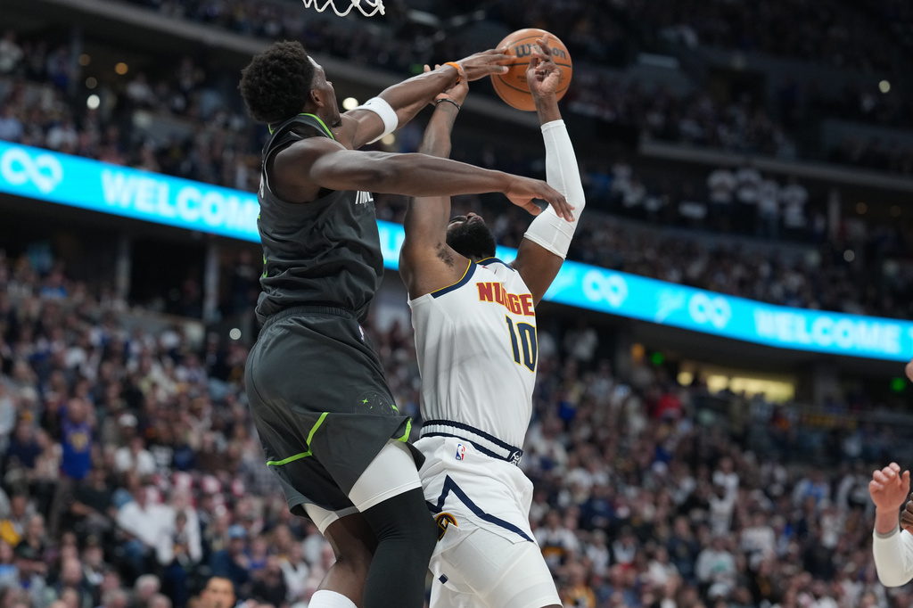 Minnesota Timberwolves guard Anthony Edwards, left, blocks a shot by Denver Nuggets guard Tim Hardaway Jr., right, in the first half in Game 1 of a first-round NBA playoffs basketball series, Saturday, April 18, 2026, in Denver. (AP Photo/David Zalubowski)