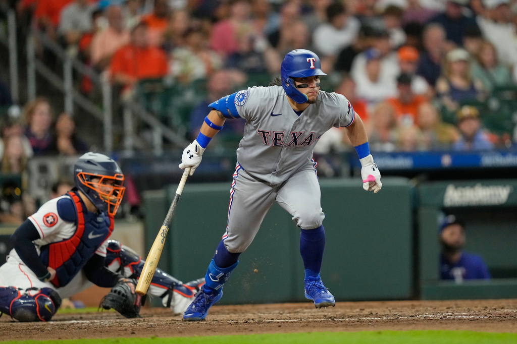 Texas Rangers' Alejandro Osuna, right, watches his RBI single in front of Houston Astros catcher Yainer Diaz during the fourth inning of a baseball game Saturday, Aug. 1, 2026, in Houston. (AP Photo/David J. Phillip)