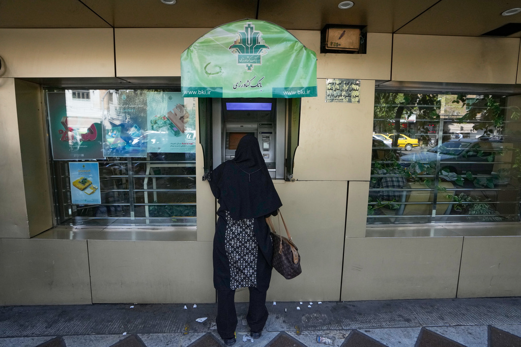 A woman uses an ATM in downtown Tehran, Iran, Monday, Aug. 24, 2026. (AP Photo/Vahid Salemi)
