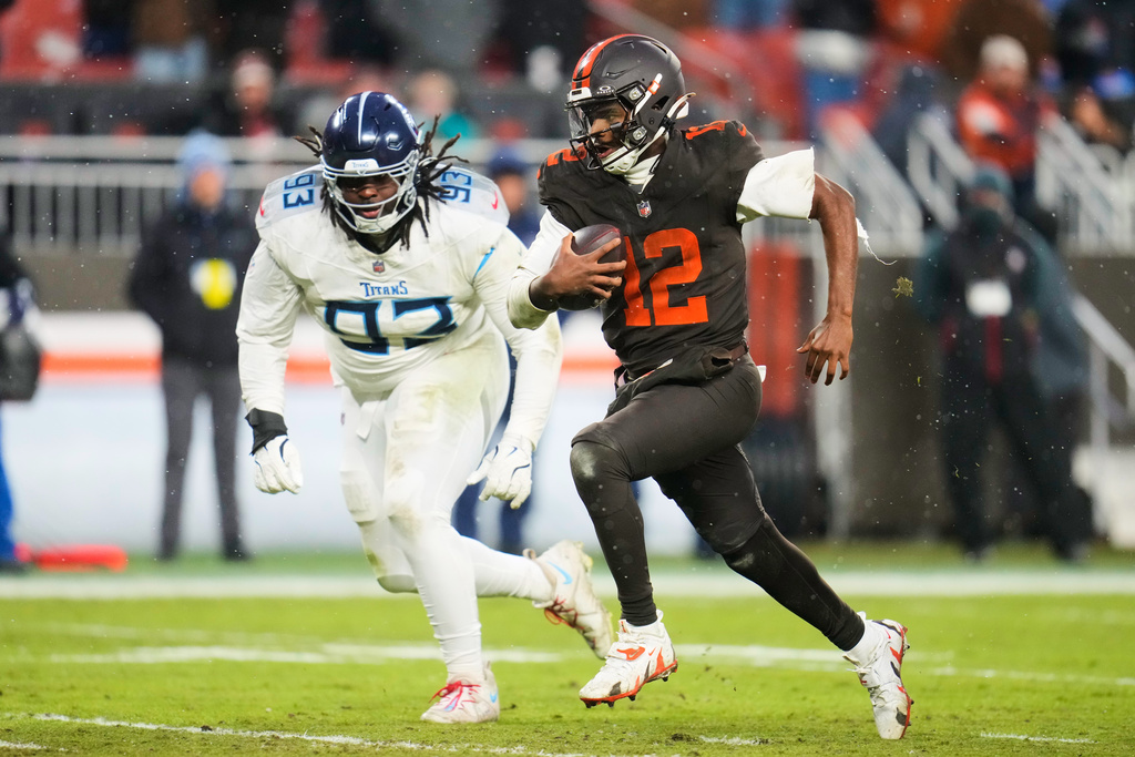 Cleveland Browns quarterback Shedeur Sanders (12) runs the ball for a touchdown as Tennessee Titans defensive tackle T'Vondre Sweat (93) gives chase in the second half of an NFL football game in Cleveland, Sunday, Dec. 7, 2025. (AP Photo/Sue Ogrocki)
