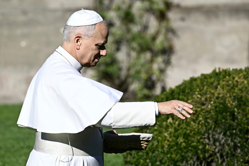 Pope Leo XIV feeds fishes of a pond during the inauguration of the "Borgo Laudato Si'" Advanced Training Center, at the papal summer residence in Castel Gandolfo, Italy, Friday Sept. 5, 2025. (Filippo Monteforte, Pool via AP)