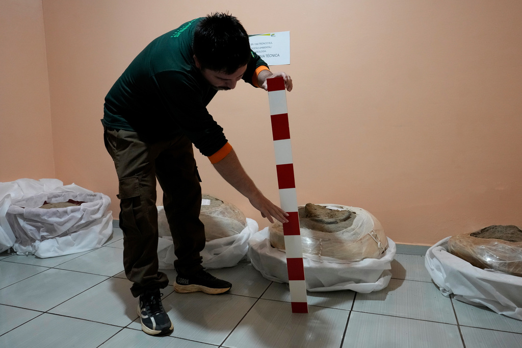 Archaeologist Manoel Fabiano da Silva Santos shows a soil layer scale while explaining the historical timeline at National Department of Transport Infrastructure in Macapa, Amapa state, Brazil, Saturday, March 14, 2026. (AP Photo/Eraldo Peres)