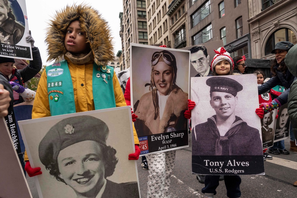 Girl Scout troops hold pictures of veterans as they march during the Veterans Day parade, Tuesday, Nov. 11, 2025, in New York. (AP Photo/Yuki Iwamura)
