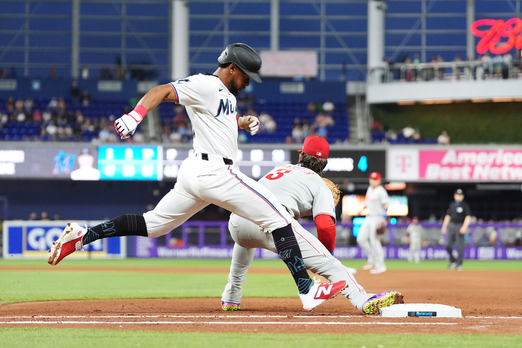 Miami Marlins' Otto Lopez, left, makes it safely to first past Philadelphia Phillies first baseman Bryce Harper during the fourth inning of a baseball game, Monday, May 4, 2026, in Miami. (AP Photo/Rebecca Blackwell)