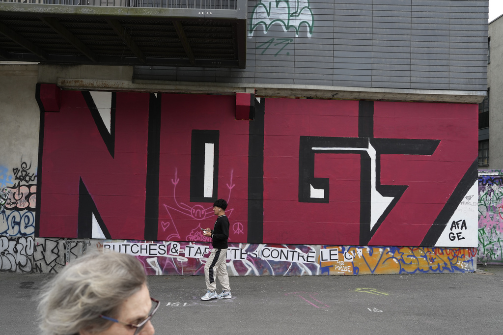 A man walks past a mural against the upcoming G7 summit, in Geneva, Switzerland, Monday, June 8, 2026. (AP Photo/Baz Ratner)