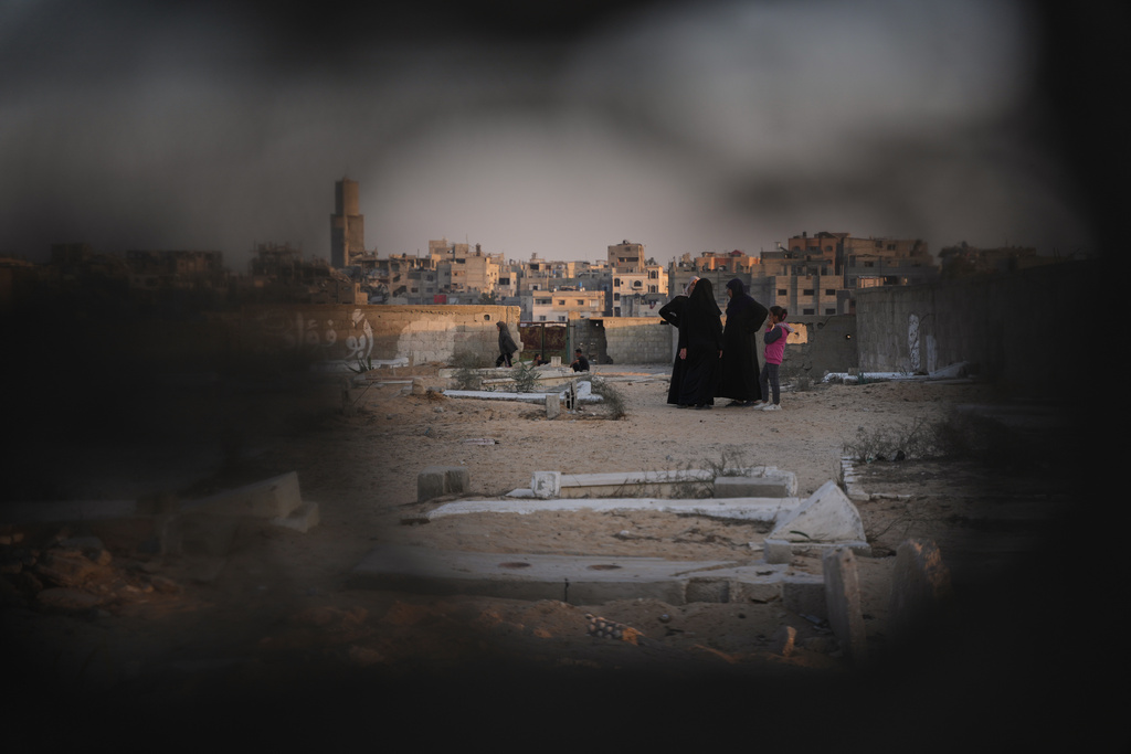 Palestinian women stand at a cemetery in Khan Younis, where a makeshift tent camp for displaced people was set up, in the southern Gaza Strip, Friday, Oct. 31, 2025. (AP Photo/Abdel Kareem Hana)