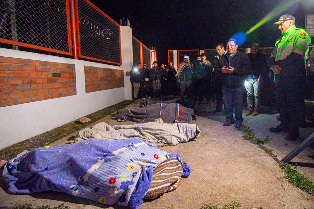 Residents stand next to the covered bodies of neighbors who were killed after an earthquake struck Pumpuya, Peru, Sunday, July 19, 2026. ( AP Photo/Javier Ninanya)
