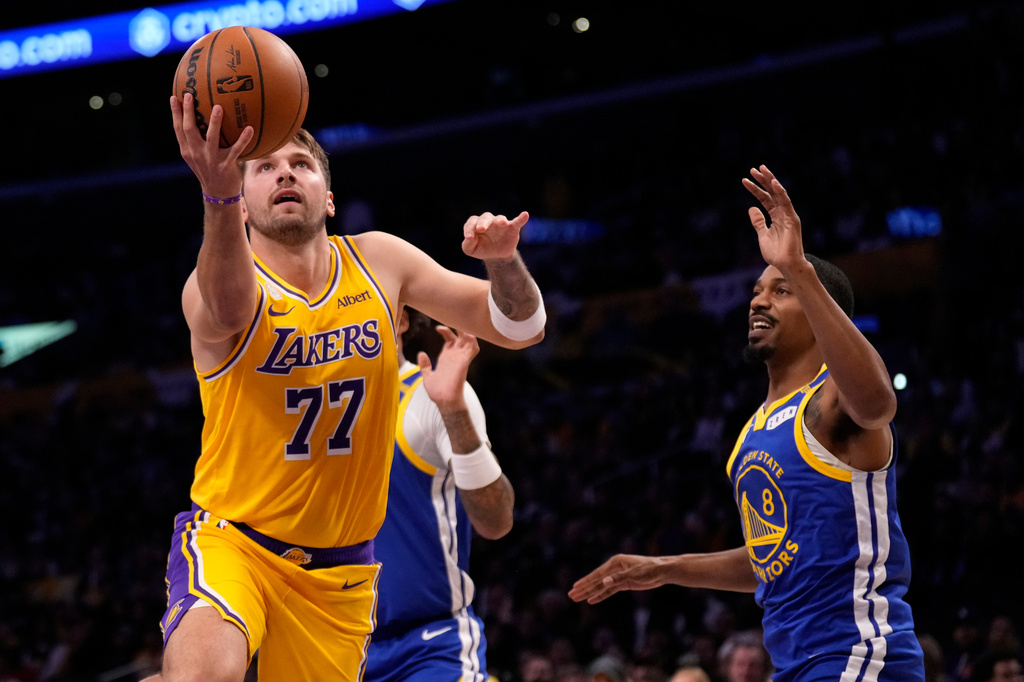 Los Angeles Lakers forward/guard Luka Doncic, left, shoots as Golden State Warriors guard De'anthony Melton defends during the first half of an NBA basketball game Wednesday, Oct. 21, 2026, in Los Angeles. (AP Photo/Mark J. Terrill)