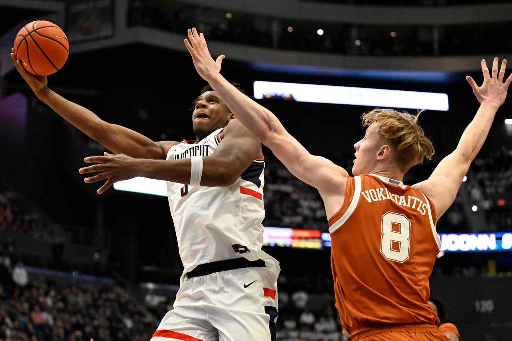 UConn forward Tarris Reed Jr., left, shoots as Texas center Matas Vokietaitis (8) defends in the first half of an NCAA college basketball game, Friday, Dec. 12, 2025, in Hartford, Conn. (AP Photo/Jessica Hill)
