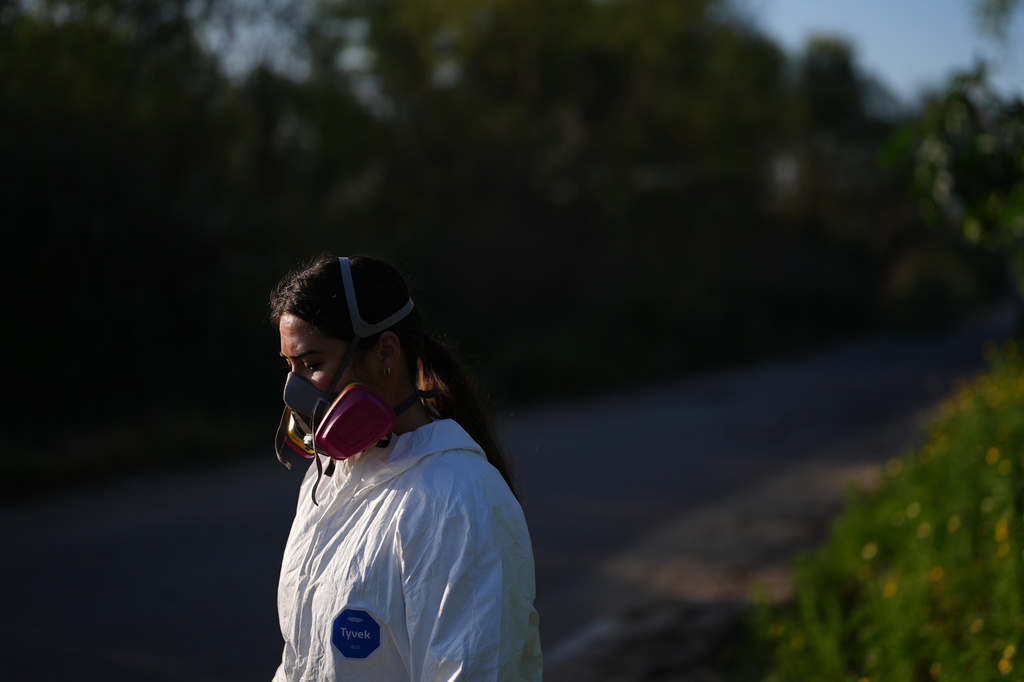Maddie Tibayan pauses while wearing a respirator while collecting a water sample of the Tijuana River, as part of a research team from the University of California, San Diego, Wednesday, March 11, 2026, in San Diego. (AP Photo/Gregory Bull)