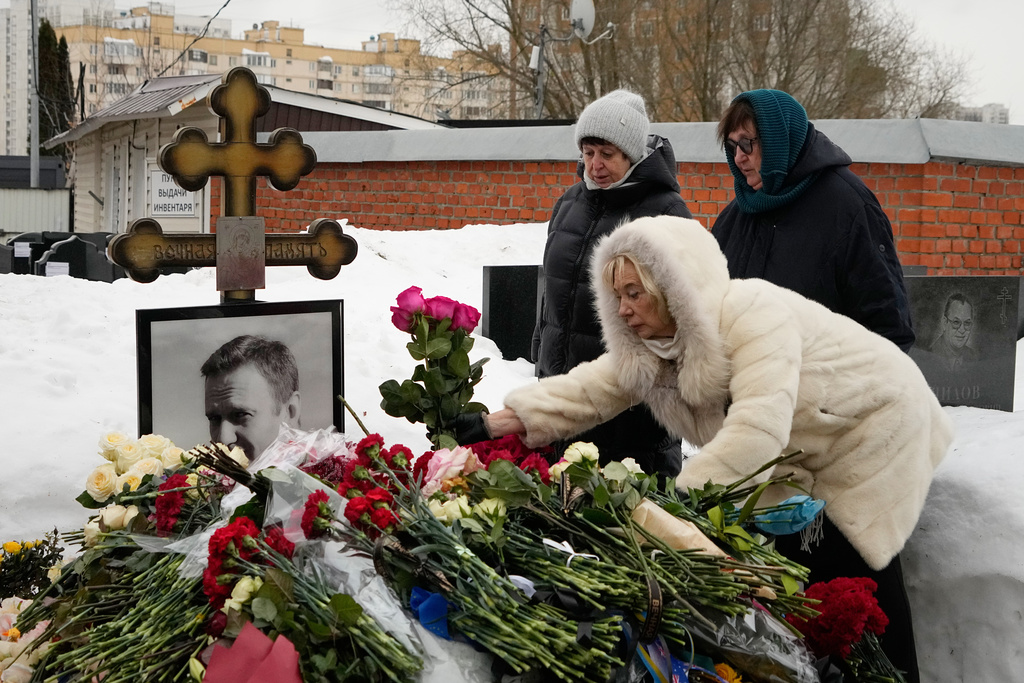 Late Russian opposition leader Alexei Navalny's mother Lyudmila Navalnaya, right, and his mother-in-law Alla Abrosimova, center, lay flowers at his grave, two years after his death, at the Borisovskoye Cemetery in Moscow, on Monday, Feb. 16, 2026. (AP Photo/Alexander Zemlianichenko)
