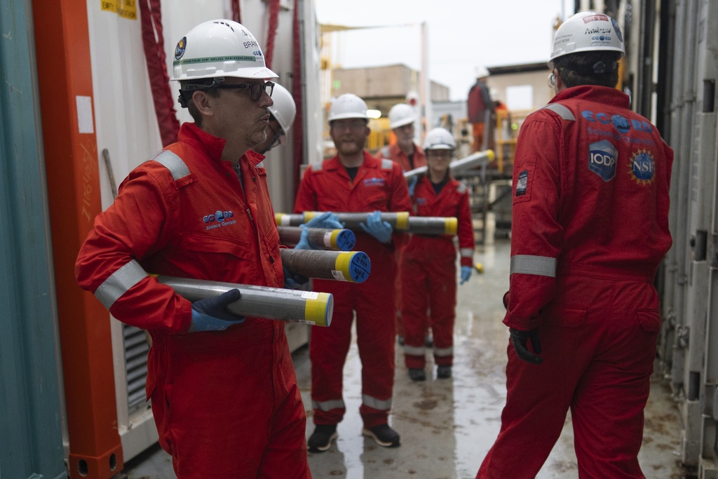 Expedition 501 researchers, including Brandon Dugan, Expedition 501 co-chief scientist, carry cores to a cold storage container aboard the Liftboat Robert platform, in the North Atlantic, Sunday, July 20, 2025. (AP Photo/Carolyn Kaster)