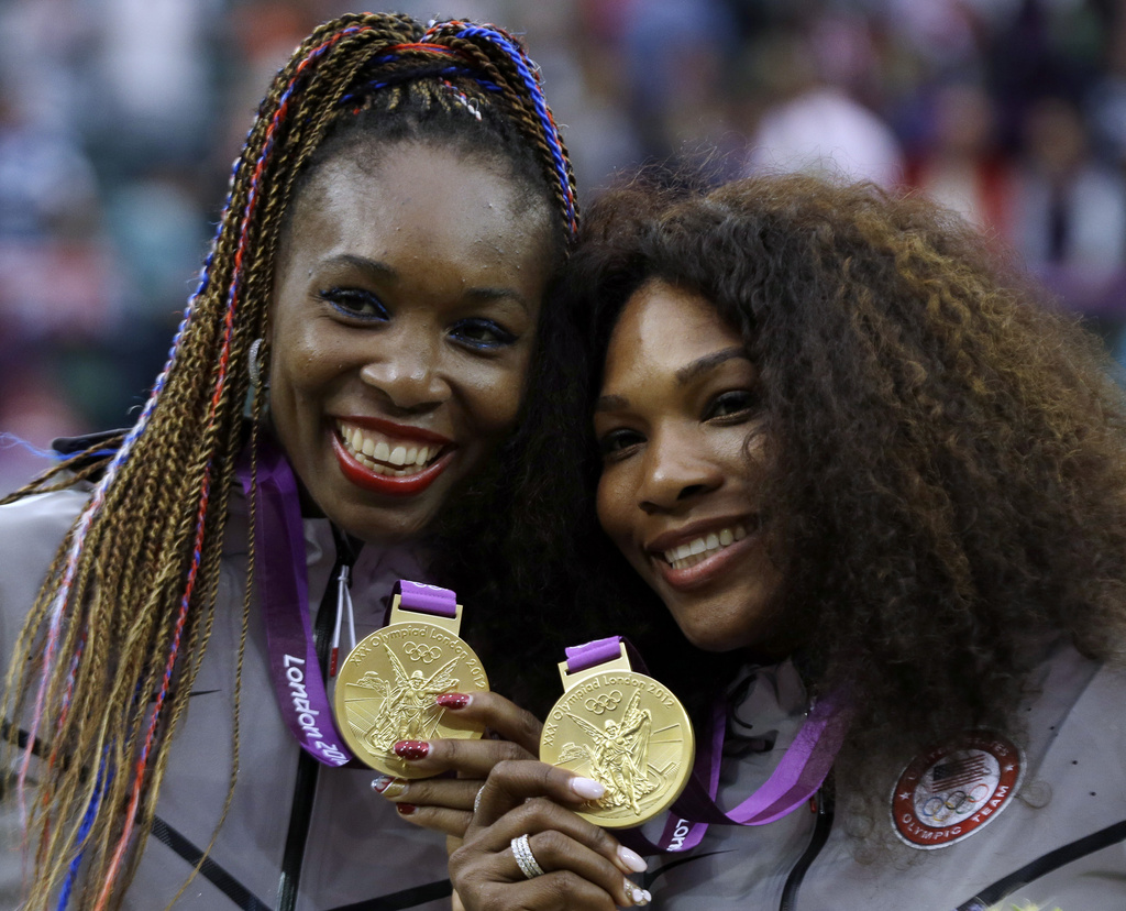 FILE - Venus Williams, left, and Serena Williams of the United States showing their gold medals in women's doubles at the All England Lawn Tennis Club in Wimbledon, London at the 2012 Summer Olympics, Aug. 5, 2012. (AP Photo/Elise Amendola, File)