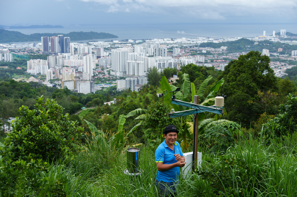 Durian farmer Kie Kim Hwa stands beside a weather and climate sensor station overlooking Penang Island in Balik Pulau, Malaysia, Wednesday, June 24, 2026. (AP Photo/Vincent Thian)