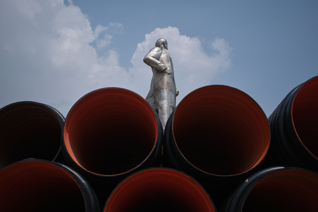 A statue of Vladimir Lenin, which until 2011 stood in the center of the city, pokes out from industrial pipes on the outskirts of Khujand, Tajikistan, Sunday, May 3, 2026. (AP Photo/Jon Orbach)