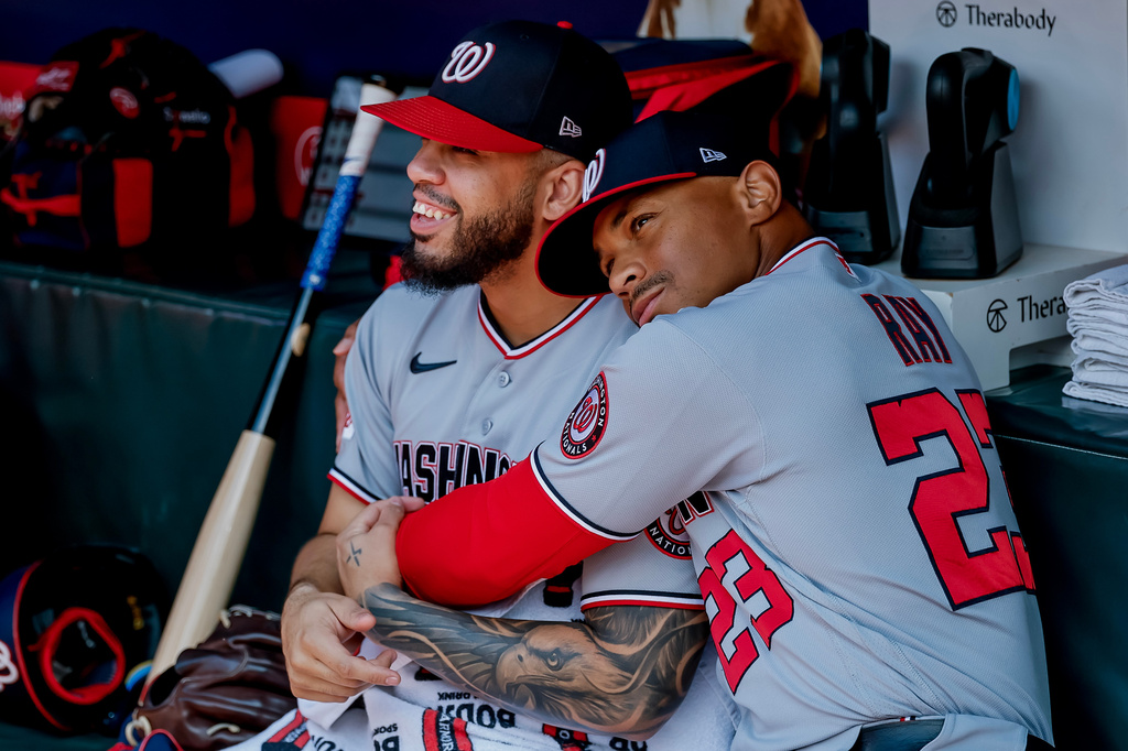 Washington Nationals first baseman Luis García Jr., left, is hugged in the dugout by first base coach Corey Ray (23) after he was scratched from the starting lineup before a baseball game against the Atlanta Braves, Sunday, Aug. 2, 2026, in Atlanta. (AP Photo/Erik S. Lesser)