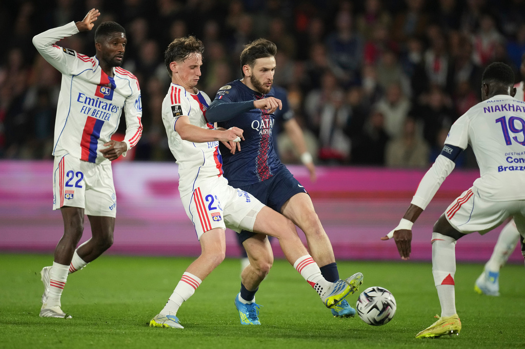 PSG's Khvicha Kvaratskhelia, centre right, and Lyon's Thiago Almada challenge for the ball during the French League One soccer match between Paris Saint-Germain and Olympique Lyon in Paris, France, Sunday, April 19, 2026. (AP Photo/Christophe Ena)
