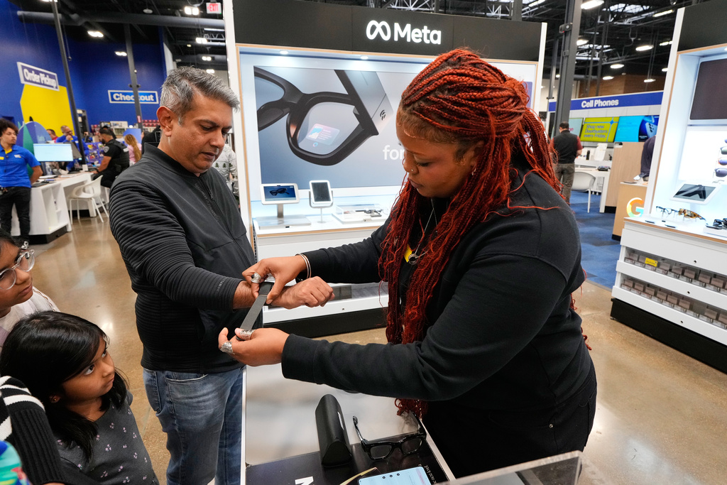 Aamir Ghulamani of Carrollton, Texas, gets help from Sydney Rogers, a Meta specialist at Best Buy as Ghulamani samples the glasses, Wednesday, Nov. 26, 2025, in Dallas. (AP Photo/Tony Gutierrez)