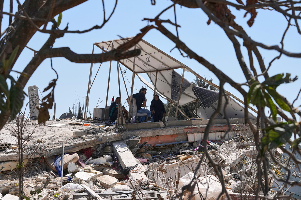 A Lebanese family takes shade under the damaged solar panels of their destroyed house in the village of Zawtar al-Gharbieh, south Lebanon, Wednesday, Aug. 5, 2026. (AP Photo/Mohammed Zaatari)