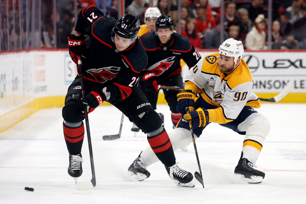 Carolina Hurricanes' Alexander Nikishin (21) battles for the puck with Nashville Predators' Ryan O'Reilly (90) during the first period of an NHL hockey game in Raleigh, N.C., Saturday, Dec. 6, 2025. (AP Photo/Karl DeBlaker)