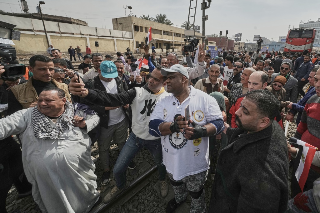 Egyptian wrestler Ashraf Mahrous, also known as Kabonga, is greeted by supporters as he prepares to pull a train nearly 10 meters (33 feet) at Ramses Station in Cairo, Egypt, while Guinness World Record observers look, Thursday, March 13, 2025. (AP Photo/Amr Nabil)