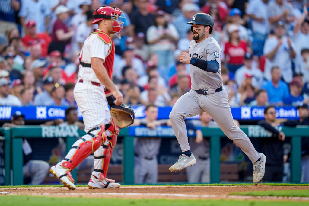 New York Yankees' Austin Wells, right, comes in to score on the single by Cody Bellinger as Philadelphia Phillies catcher J.T. Realmuto, left, looks on during the sixth inning of a baseball game, Saturday, July 25, 2026, in Philadelphia. (AP Photo/Chris Szagola)