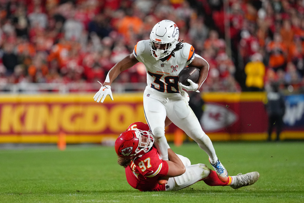 Denver Broncos running back Jaleel McLaughlin (38) rushes for a first down as Kansas City Chiefs defensive end Ashton Gillotte (97) tries to stop him during the first half of an NFL football game Thursday, Dec. 25, 2025, in Kansas City, Mo. (AP Photo/Ed Zurga)