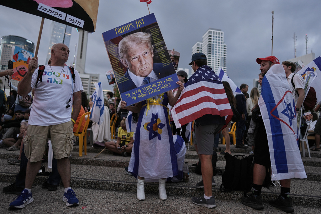 A woman holds an image of U.S. President Donald Trump during a gathering at a plaza known as hostages square in Tel Aviv, Israel, Monday, Oct. 13, 2025, before the release of Israeli hostages held in Gaza. (AP Photo/Oded Balilty)