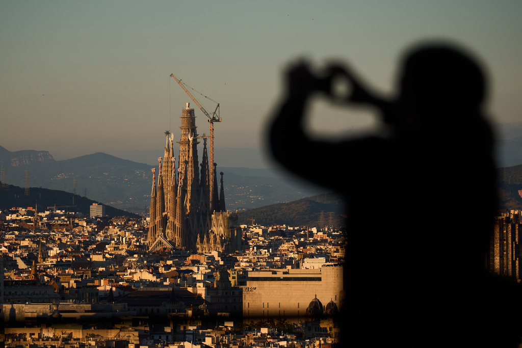 A tourist takes photos at the Sagrada Familia basilica, which became the world's tallest church on Thursday after a section of its central tower was lifted into place, in Barcelona, Spain, Oct. 30, 2025. (AP Photo/Emilio Morenatti)