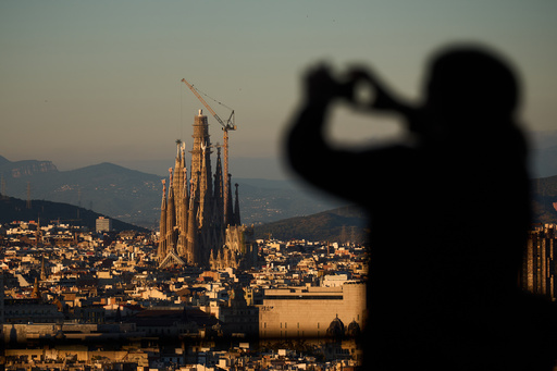 A tourist takes photos at the Sagrada Familia basilica, which became the world's tallest church on Thursday after a section of its central tower was lifted into place, in Barcelona, Spain, Oct. 30, 2025. (AP Photo/Emilio Morenatti) A tourist takes photos at the Sagrada Familia basilica, which became the world's tallest church on Thursday after a section of its central tower was lifted into place, in Barcelona, Spain, Oct. 30, 2025. (AP Photo/Emilio Morenatti)