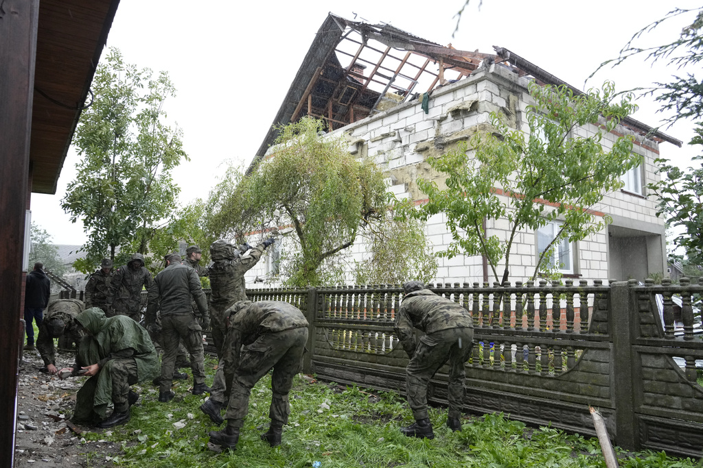 Territorial defense officers clean up debris from the destroyed roof of a house, after Russian drones violated Polish airspace during an attack on Ukraine, in Wyryki near Lublin, Poland, Thursday, Sept. 11, 2025. (AP Photo/Czarek Sokolowski)