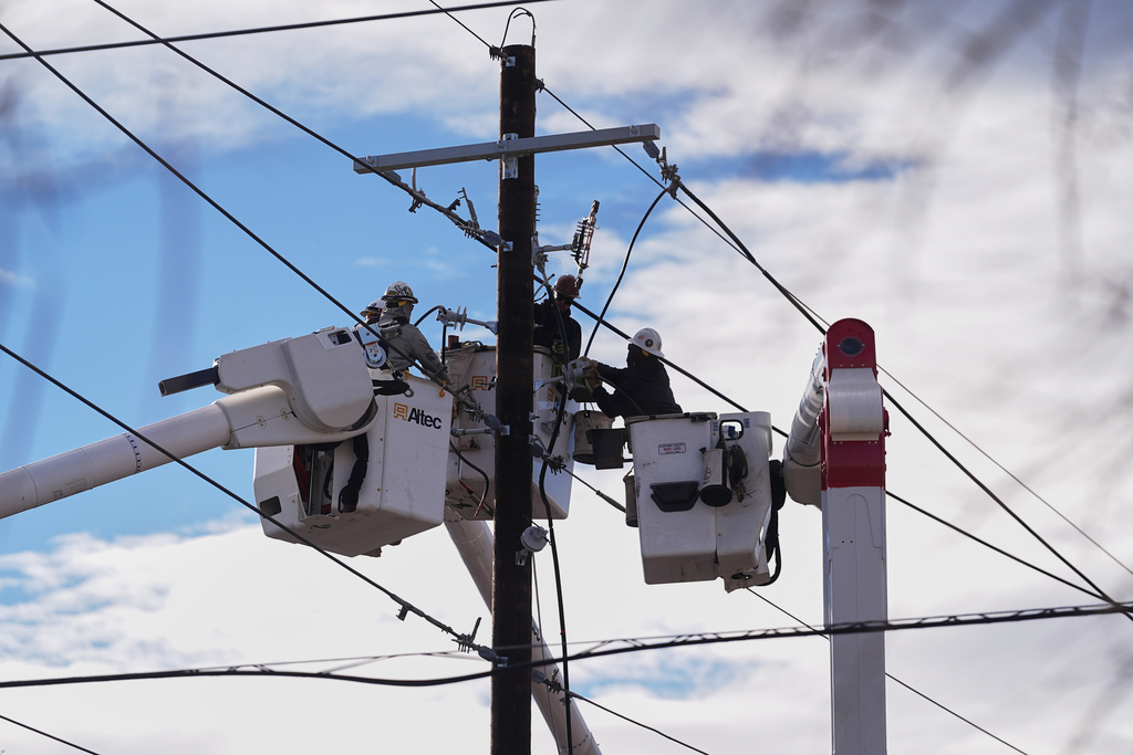 Xcel Energy workers toil to repair power lines on a street closed after hurricane-force winds whipped through the metropolitan area and interrupted service to residents Thursday, Dec. 18, 2025, in Denver. (AP Photo/David Zalubowski)
