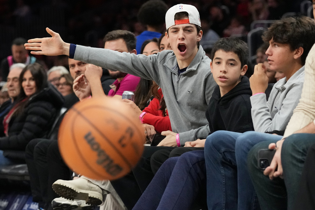 Lucas Gonzalez, 16, center, reacts to a play as he sits courtside with Matias Gonzalez, 13, second from right, and Sergio Masvidal, 15, right, during the first half of an NBA basketball game, Sunday, Feb. 1, 2026, in Miami. (AP Photo/Lynne Sladky)