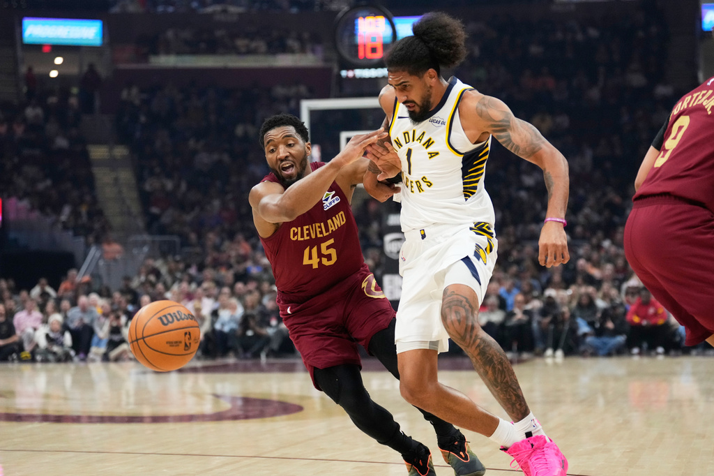 Cleveland Cavaliers guard Donovan Mitchell (45) knocks the ball away from Indiana Pacers forward Obi Toppin (1) in the first half of an NBA basketball game in Cleveland, Sunday, April 5, 2026. (AP Photo/Sue Ogrocki)