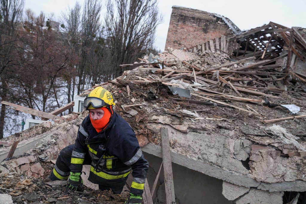 A rescue worker climbs onto the roof of apartment building damaged after a Russian strike on Kyiv, Ukraine, on Saturday, Dec. 27, 2025. (AP Photo/Evgeniy Maloletka)