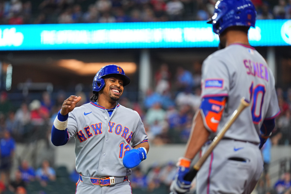New York Mets' Francisco Lindor, left, is greeted near home plate by Marcus Semien after scoring on a single by teammate Carson Benge, not visible, during the first inning of a baseball game against the Texas Rangers, Thursday, Sept. 24, 2026, in Arlington, Texas. (AP Photo/Julio Cortez)