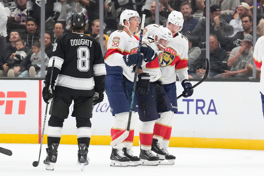 Florida Panthers left wing Brad Marchand, second from right, is helped off the ice by left wing Brady Tkachuk, second from left, and defenseman Niko Mikkola after he was injured as Los Angeles Kings defenseman Drew Doughty looks on during the second period of an NHL hockey game Tuesday, Oct. 6, 2026, in Los Angeles. (AP Photo/Mark J. Terrill)