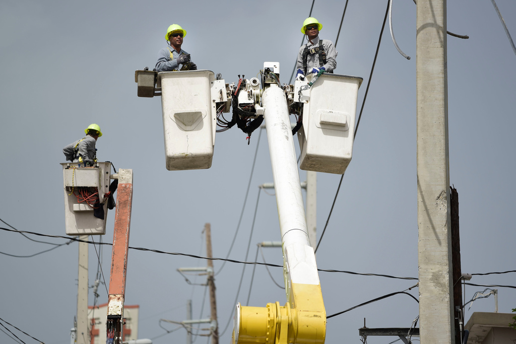 FILE - Puerto Rico Electric Power Authority workers repair distribution lines damaged by Hurricane Maria in the Cantera community of San Juan, Puerto Rico, Oct. 19, 2017. (AP Photo/Carlos Giusti, File)