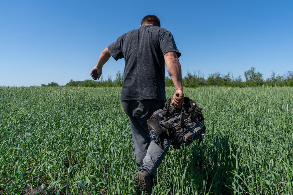 A farmer carries a fragment of a Russian drone on an agricultural field near the front line in the Kharkiv region, Ukraine, Friday, May 22, 2026. (AP Photo/Andrii Marienko)