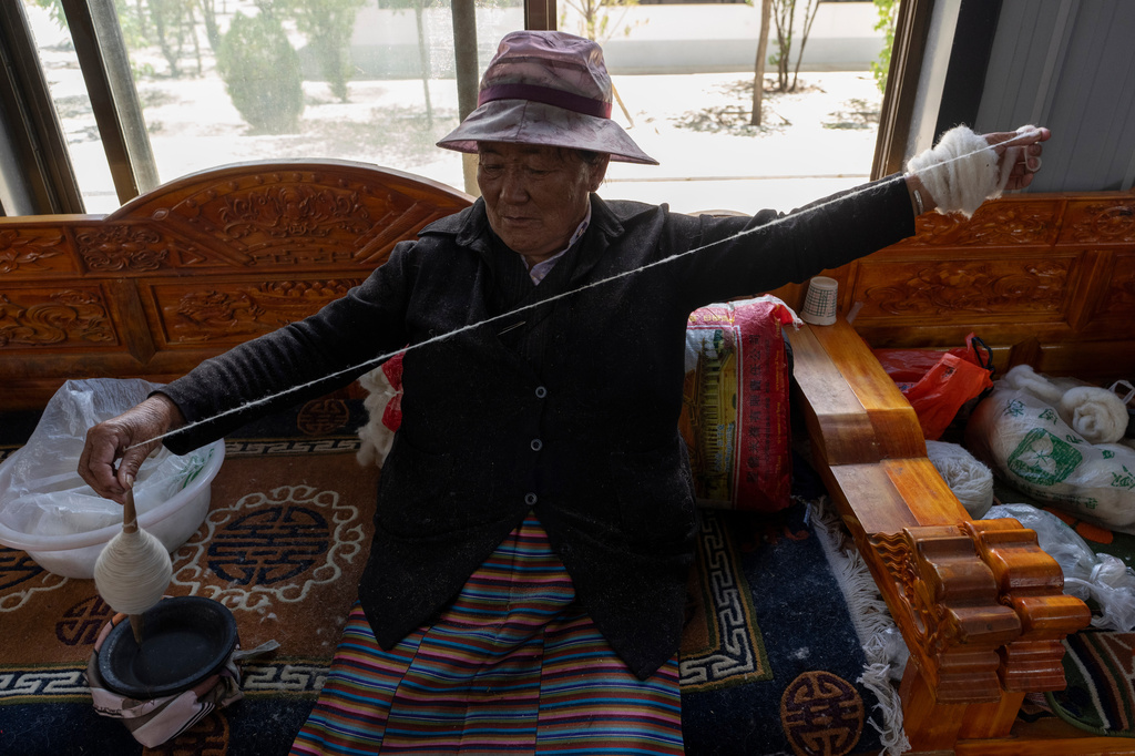 A worker pulls wool into a yarn at the Ethnic Huaji Handwoven Cooperative in Shannan in western China's Tibet Autonomous Region on July 23, 2026, as seen during a government organized visit for foreign journalists. (AP Photo/Ng Han Guan)
