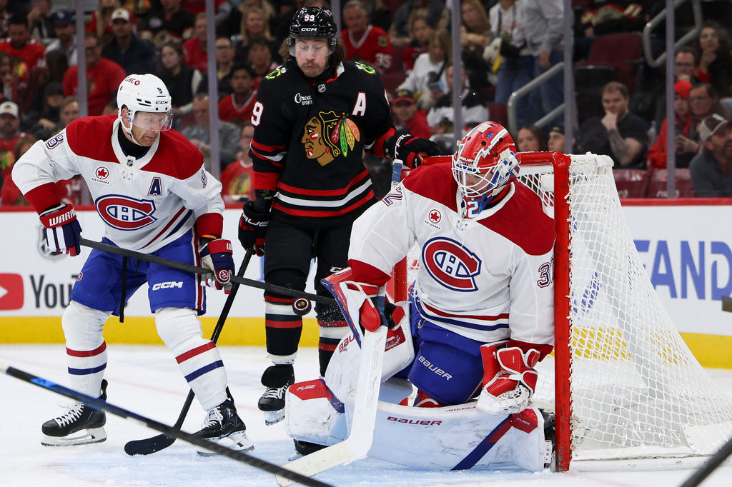Montreal Canadiens goaltender Jacob Fowler, right, makes a save as defenseman Mike Matheson, left, and Chicago Blackhawks left wing Tyler Bertuzzi, center, watch during the second period of an NHL hockey game, Friday, Oct. 23, 2026, in Chicago. (AP Photo/Jessie Alcheh)