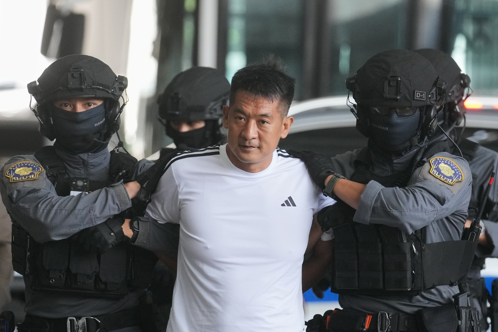 She Zhijiang, an alleged transnational crime kingpin accused by Beijing of having run illegal online gambling operations, is escorted by police at Suvarnabhumi International Airport in Thailand's Samut Prakarn province ahead of being extradited to China, Wednesday, Nov. 12, 2025. (AP Photo/Sakchai Lalit)