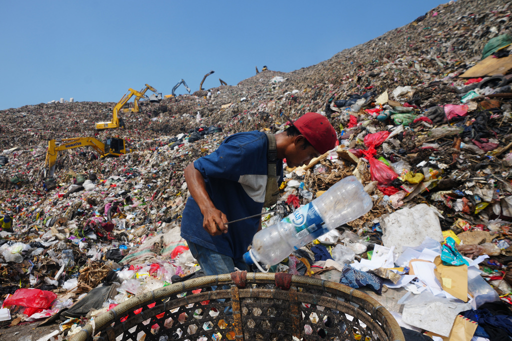 Komaruddin, a waste picker, looks for recyclable items in a pile of garbage at the Bantargebang landfill on the outskirts of Jakarta, Indonesia, Monday, July 6, 2026. (AP Photo/Tatan Syuflana)