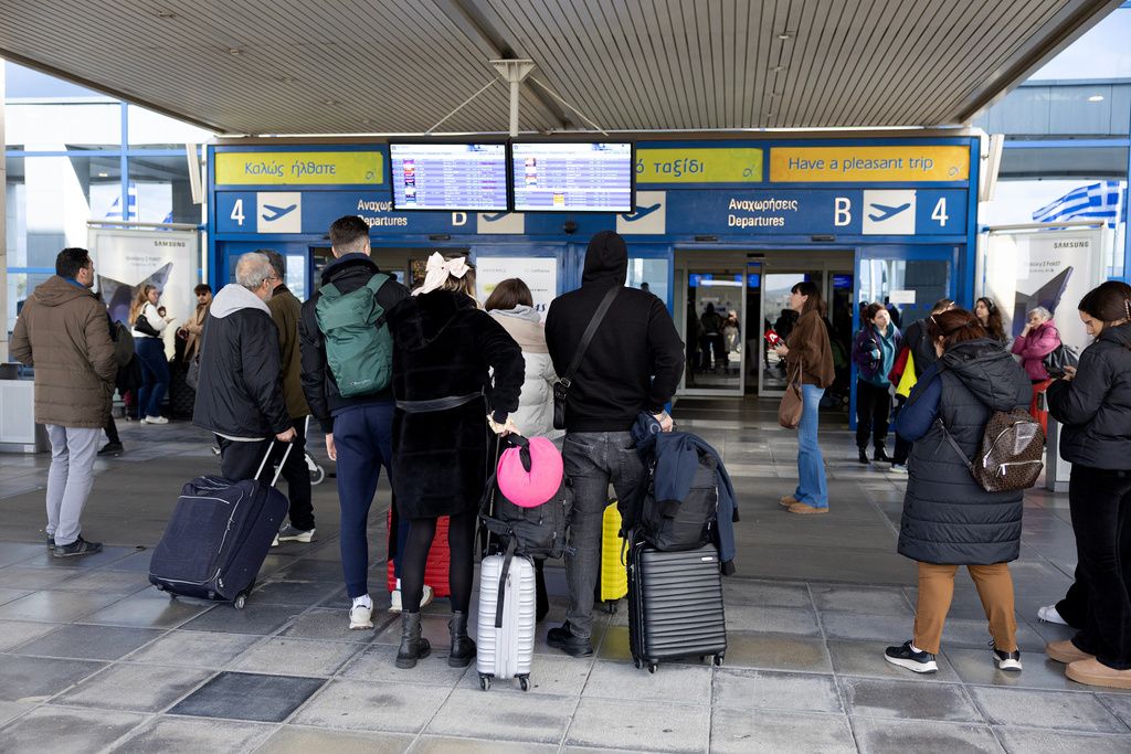 Passengers check a flight information board outside Athens' Eleftherios Venizelos international airport in Athens, Greece, Sunday, Jan. 4, 2026, as many flights were disrupted across Greece. (AP Photo/Yorgos Karahalis)